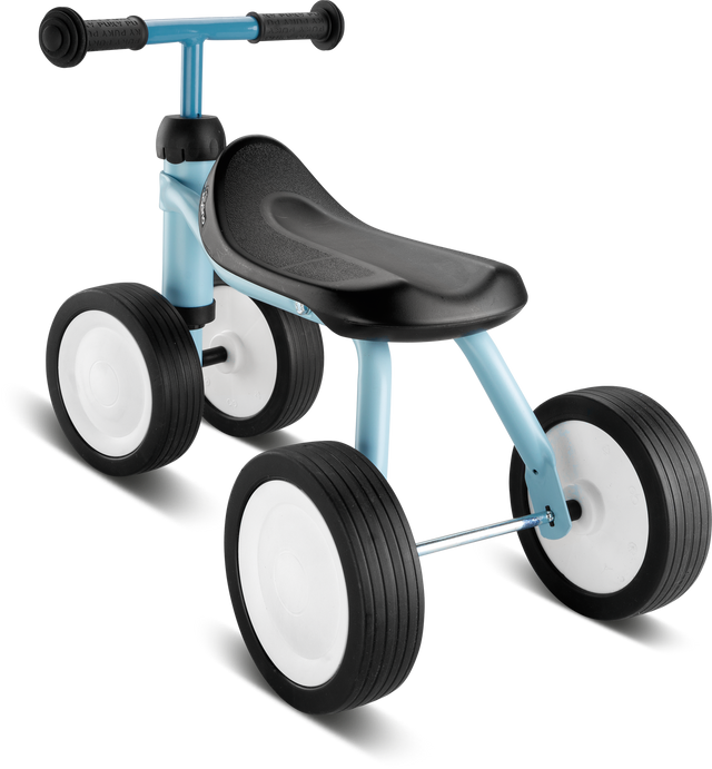 Babycykeln - Pukylino - Retro blå från PUKY är en liten blå och svart trehjuling med stora vita hjul. Den har ett svart säte och ett styre utan pedaler, vilket tyder på att den är designad som en balanscykel för små barn att driva sig framåt med fötterna, vilket förstärker barnets motorik.