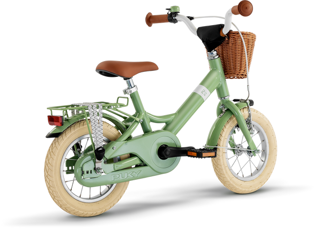 PUKY Barncykel - 12" - 3 år - 1 Gear, eller Puky Youke 12 Classic, är en charmig grön cykel för barn runt 3 år. Den har krämfärgade däck, ett brunt säte, flätad korg på styret, ett bakre metallställ, träningshjul och ett kedjeskydd.