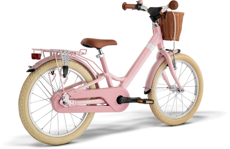 PUKY Barncykel 18" för barn i 5-årsåldern har en rosa ram, vita däck, en brun lädersadel och handtag, en flätad korg framtill och ett bakre metallställ. Designen PUKY YOUKE 18 Classic inkluderar ett kedjeskydd och lättviktskomponenter för enkel körning.