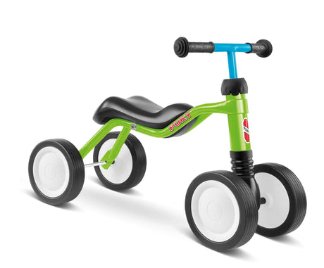 En livlig grön och blå Balanscykel - Puky Wutsch från PUKY, med svart säte och styre, är designad för små barn. Den fyrhjuliga cykeln förbättrar motoriken med sina svarta hjul med vita centra.