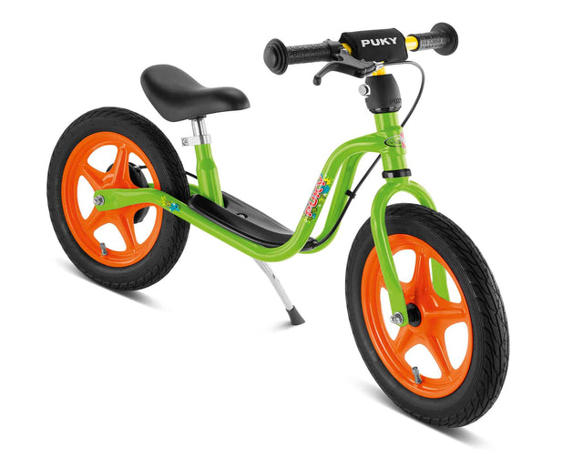PUKY Balanscykel - Lufthjul - Puky LR 1_L Br i grönt är utrustad med orange hjul och svarta luftfyllda däck. Den har en metallram, kompletterad med ett svart säte och styrhandtag, och är designad utan pedaler för att hjälpa barn att utveckla balans och koordination.