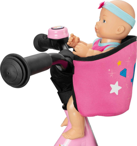 En närbild av en babydocka som sitter i en rosa Docksits för inlärningscyklar, skoter och cyklar – Puky Carry av okänd säljare. Dockan är fäst med ett blått pannband och är klädd i en rosa outfit med en blå rosett. Cykelsätet har stjärn- och diamantdesign och är fäst på styret på Puky Carry.
